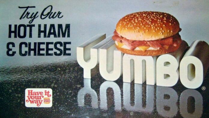 Discontinued Burger King Menu Items - Vintage advertisement featuring a hot ham and cheese sandwich on a sesame seed bun. The sandwich is placed atop large 3D letters spelling YUMBO. Text reads Try Our Hot Ham & Cheese and Have it your way, Burger King.